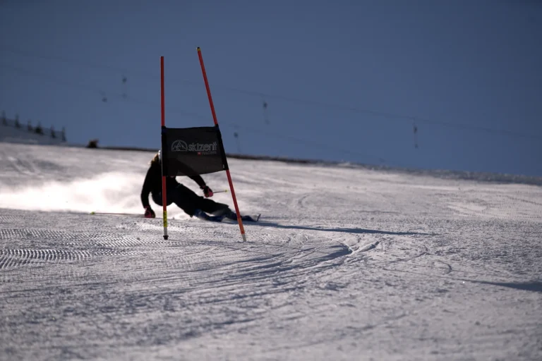 Ski racer carving a giant slalom gate at speed on a sunny race training day